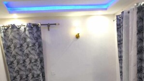 A modern living room with a sectional sofa, a glass coffee table, and a blue carpet. - Résidence le prestige (Kribi)