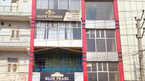 Un immeuble à plusieurs étages, sur lequel on peut voir des enseignes indiquant « Blue Pearl » et « Elite Fitness ».