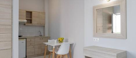A modern kitchen with wooden cabinets, a white countertop, and a dining area with a white table and chairs.