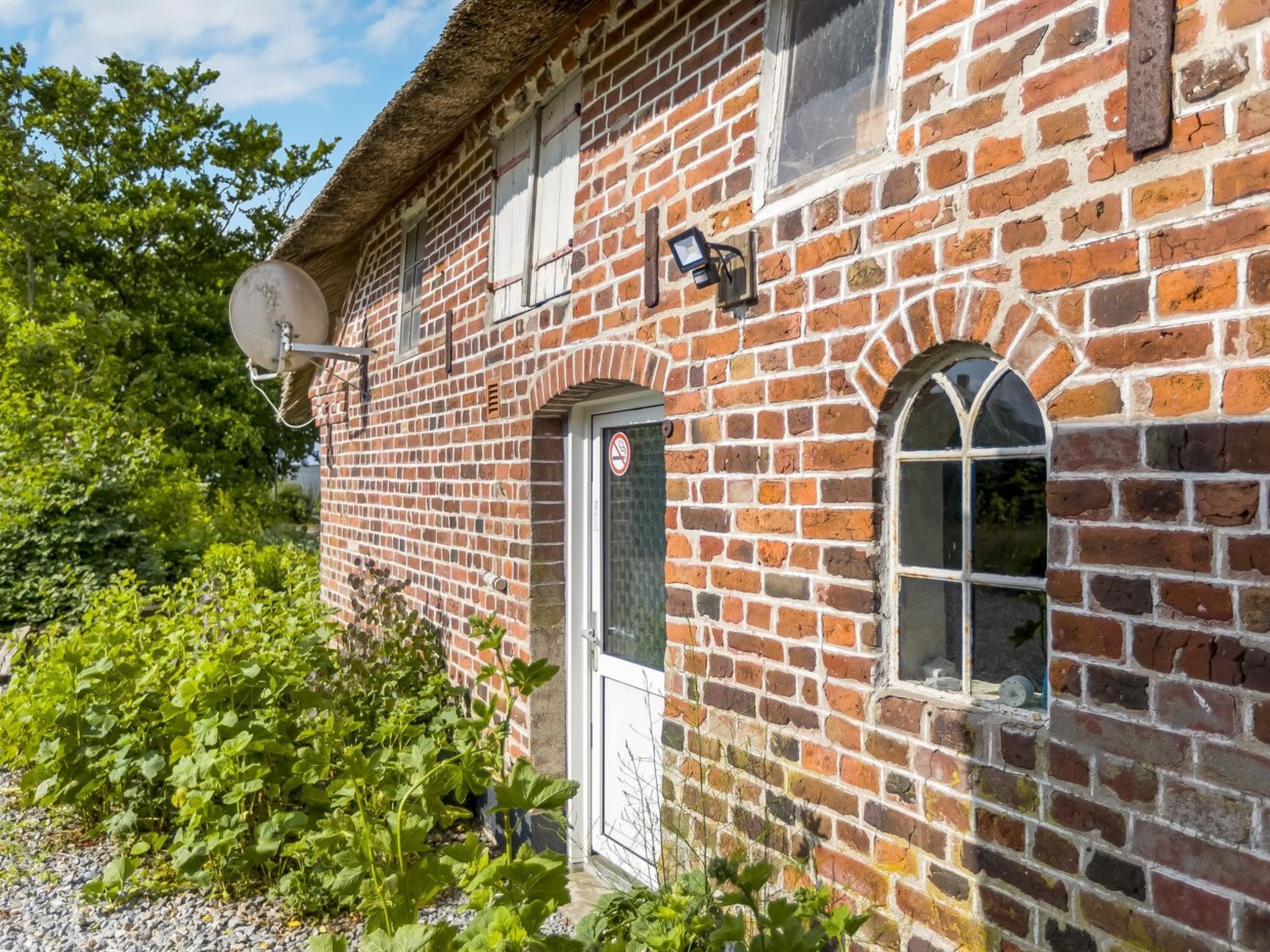 Un bâtiment en briques avec une antenne parabolique, une porte avec une enseigne et une fenêtre.