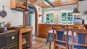A kitchen with a brick oven, wooden cabinets, and a dining area with a table and chairs.