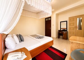 Una camera da letto con un letto, un comodino con un telefono, una scrivania e un armadio.