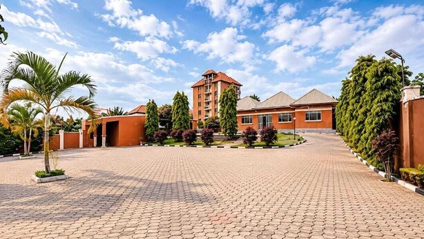 Un patio empedrado con un edificio, palmeras y cielo despejado.