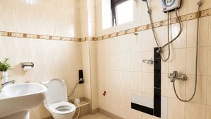 Un baño con inodoro, lavamanos, ducha y una ventana pequeña.