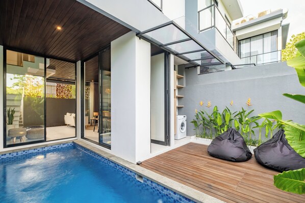 Una casa moderna con piscina, terraza de madera y amplias ventanas.