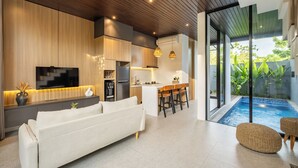 A modern kitchen with wooden cabinets, a built-in oven, and a dining area with a bar. - Private Pool Vila 8B Close Melasti Beach (Ungasan)