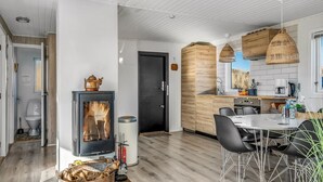 Una cocina moderna con una isla central, un comedor con sillas negras y una estufa a leña visible.