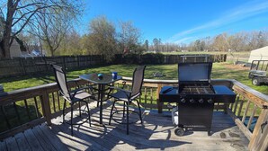 Eine Terrasse mit Grill, Stühlen und einem Tisch.
