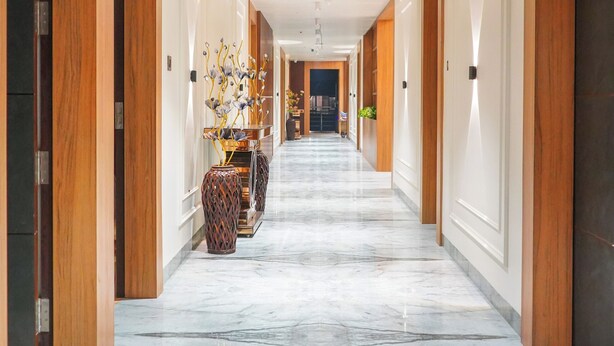 A hotel hallway with wooden paneling, marble flooring, and a central decorative arrangement. - HOTEL MEENA AURUM INN (Darbhanga)