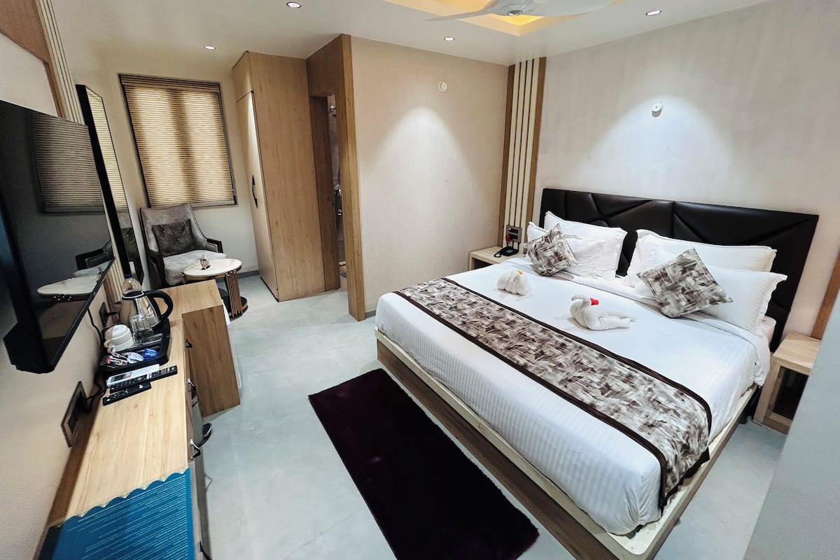 Une chambre d’hôtel moderne avec un grand lit, des tables de chevet, un bureau et un ventilateur de plafond.