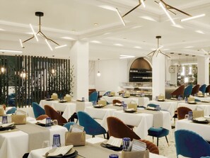 A modern dining area with tables set for service, a wine rack in the background, and a decorative bamboo wall. - Oros Paradise Hotel (Rhodes)