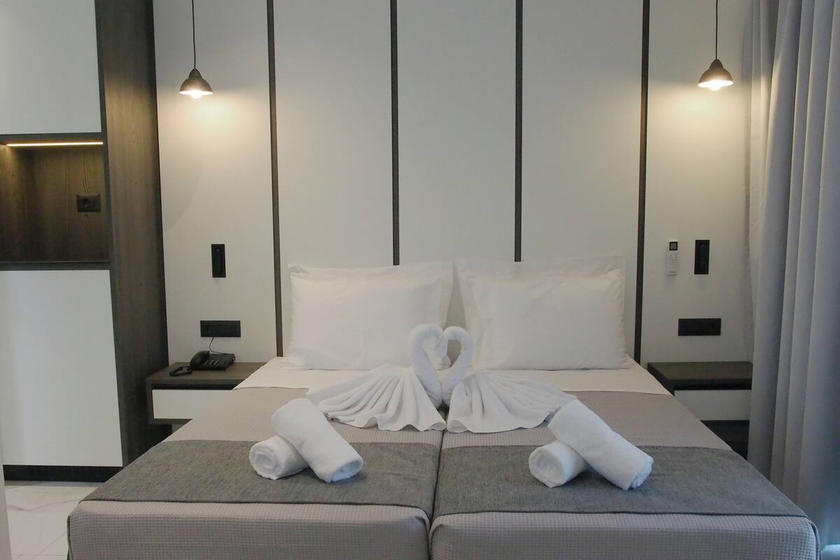 A hotel room with a bed, two bedside tables, a phone, and two wall-mounted lights.