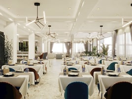 A spacious dining area with multiple tables, modern lighting fixtures, and a view of the outdoors.