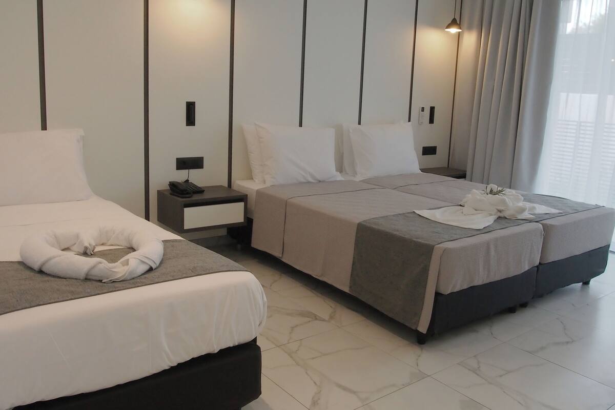 A modern hotel room with two beds, a bedside table with a phone, and a nightstand.