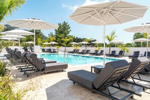 A poolside area with lounge chairs and umbrellas, a swimming pool, and greenery in the background. - Oros Paradise Hotel (Rhodes)