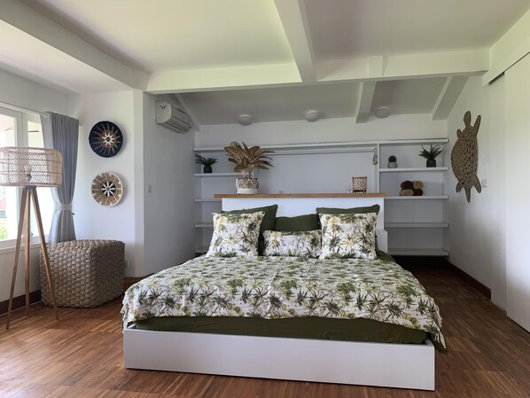A bedroom with a bed, a standing lamp, and shelves with decorative items. - Angel Bay by Triang Villas - Nazaré  (Tabanan)