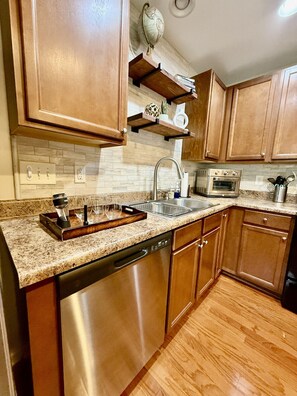 A kitchen with wooden cabinets, a granite countertop, stainless steel appliances, and a globe on the wall.