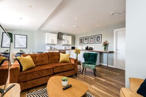 Una sala de estar moderna con un sofá marrón, una mesa de centro de madera y un sillón verde.