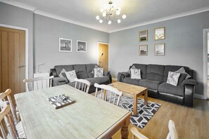 A modern living room with a dining table, two sofas, and a chandelier. - Host Stay Hope Terrace (Morpeth)