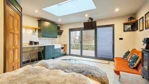 A modern room with a skylight, a sofa, a bed with a furry blanket, and a kitchen area. - Host Stay The Churchside Well (Scarborough)