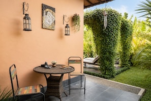 A patio with a round table, chairs, and wall-mounted lanterns. - Genie Private Villa by Travellink Bali (Ubud)