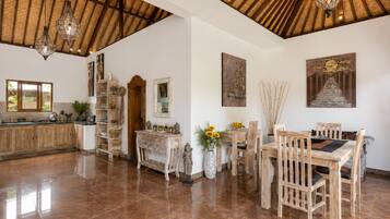 Una cocina amplia con techo de madera, un comedor con mesa y sillas de madera, y un ventanal grande.
