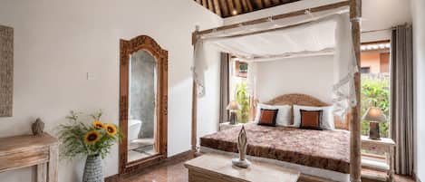 A bedroom with a four-poster bed, a large mirror, a wooden bedside table, and a vase with flowers.