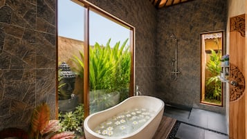 Un baño moderno con una bañera independiente, una ducha y un ventanal con vistas a la vegetación.