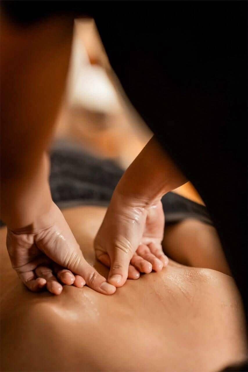 Close-up de mãos massageando as costas de uma pessoa.