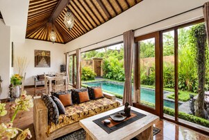 Amplia sala de estar con vista a la piscina, muebles de madera y un gran ventanal.