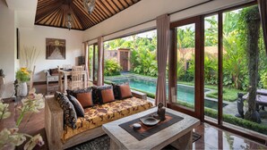 A spacious room with a large window, a wooden ceiling, and a view of a pool and garden. - Genie Private Villa by Travellink Bali (Ubud)