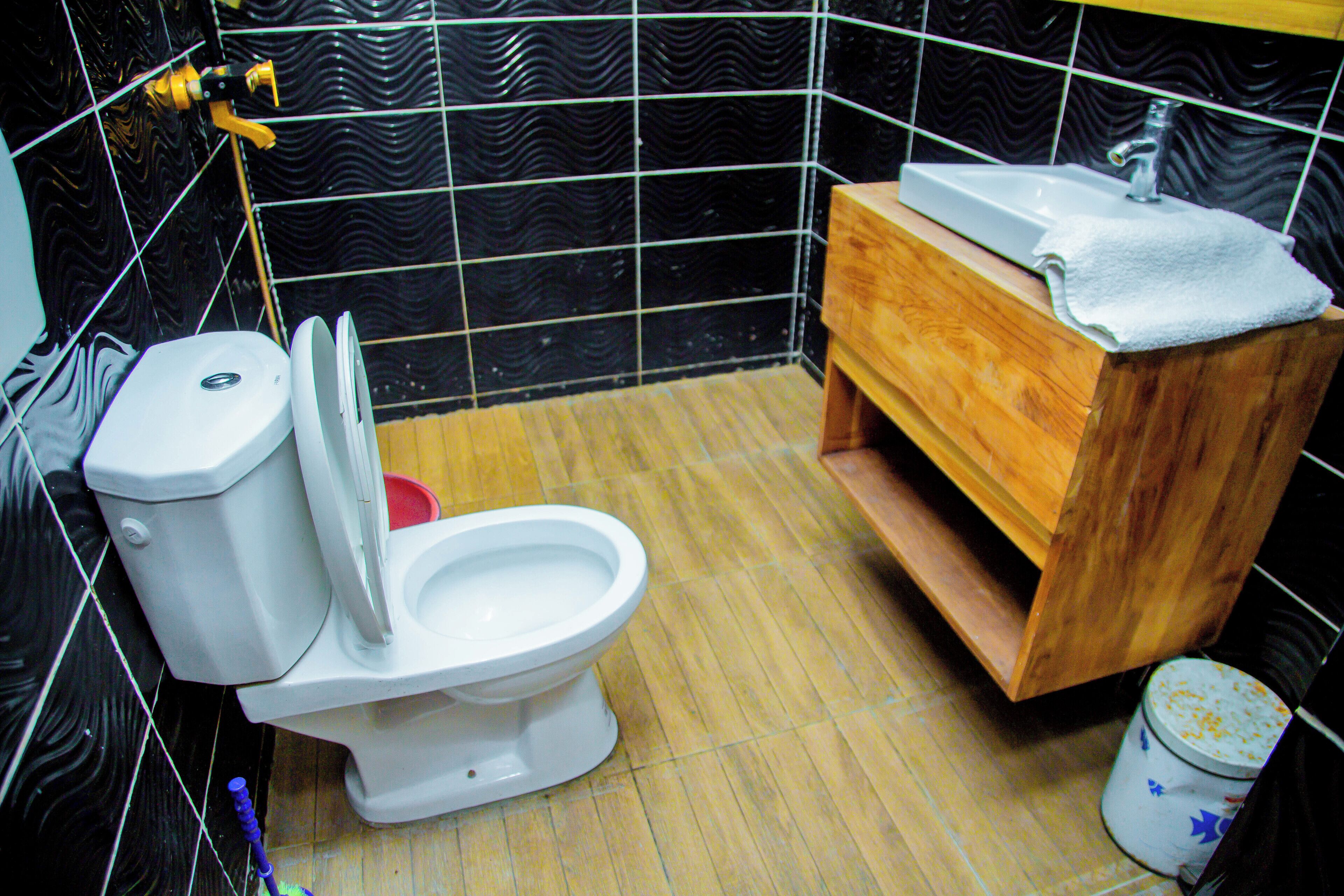 A bathroom with a toilet, sink, and wooden vanity.