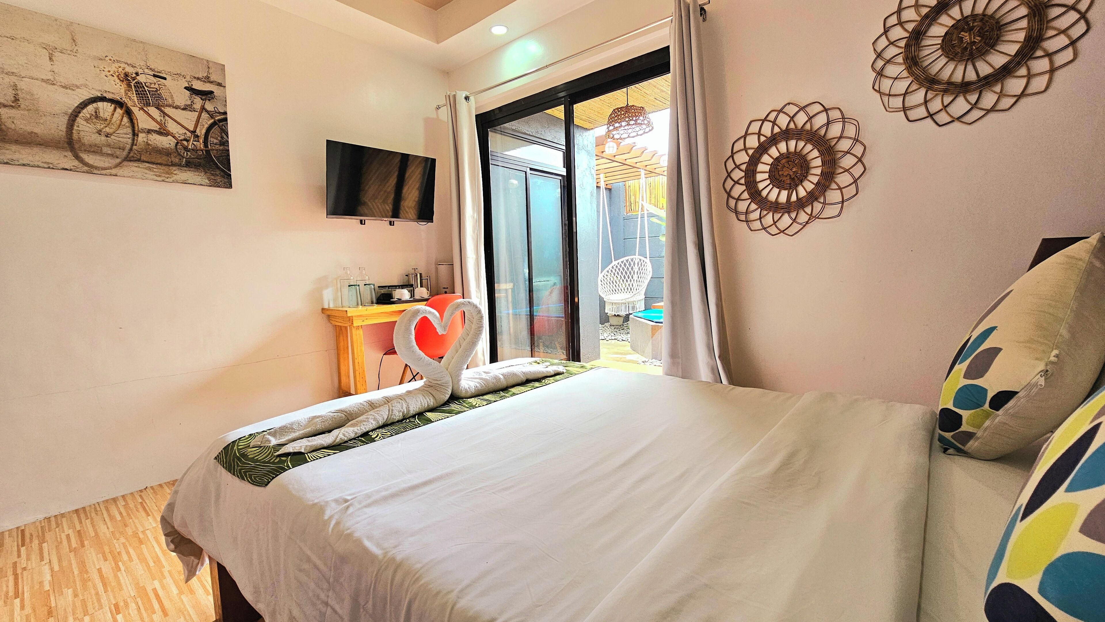 Een hotelkamer met een bed, een bureau met stoel, een televisie en decoratieve muurkunst.