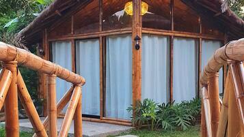 A wooden structure with a thatched roof, a gravel pathway leading to it, and a view of the interior through a window.