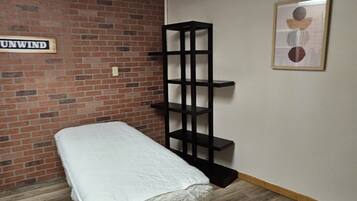 Cozy retreat with a brick wall, bench, and shelving unit, featuring a unique abstract artwork.