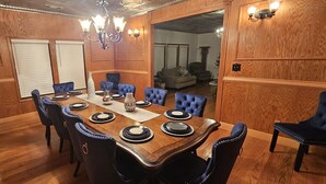 A dining room with a wooden table set for six, blue upholstered chairs, and a chandelier. - Vacation, Wedding, Retreat & Family Gathering, Spa and Theater rooms - Sleeps 30 (Manchester)