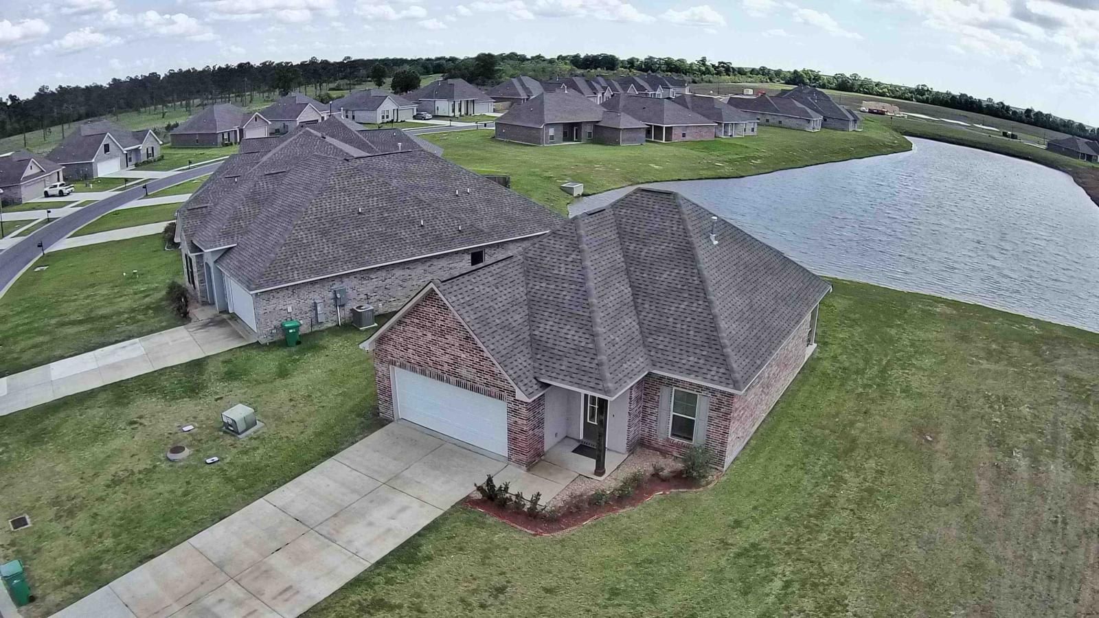 A residential area with houses, a driveway, and a large body of water.