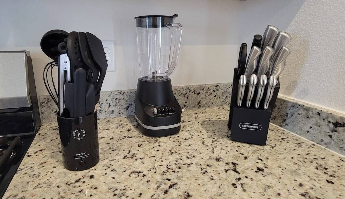 A kitchen counter with a blender, a knife holder, and a coffee maker.
