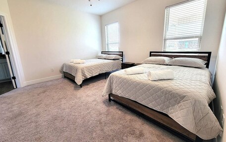 A bedroom with two beds, a ceiling fan, and a window with blinds.