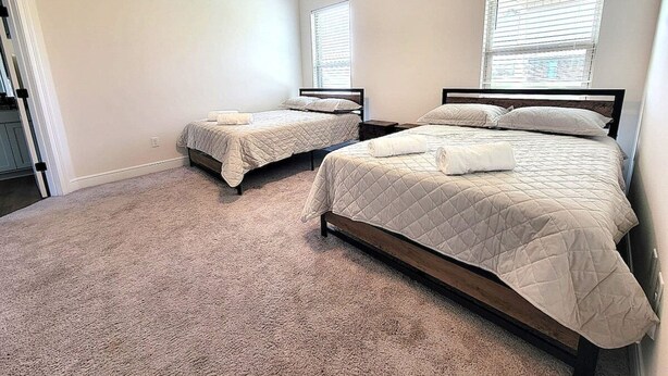 A bedroom with two beds, a ceiling fan, and a window with blinds.