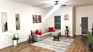 A living room with a sectional sofa, a coffee table, a rug, and a ceiling fan.
