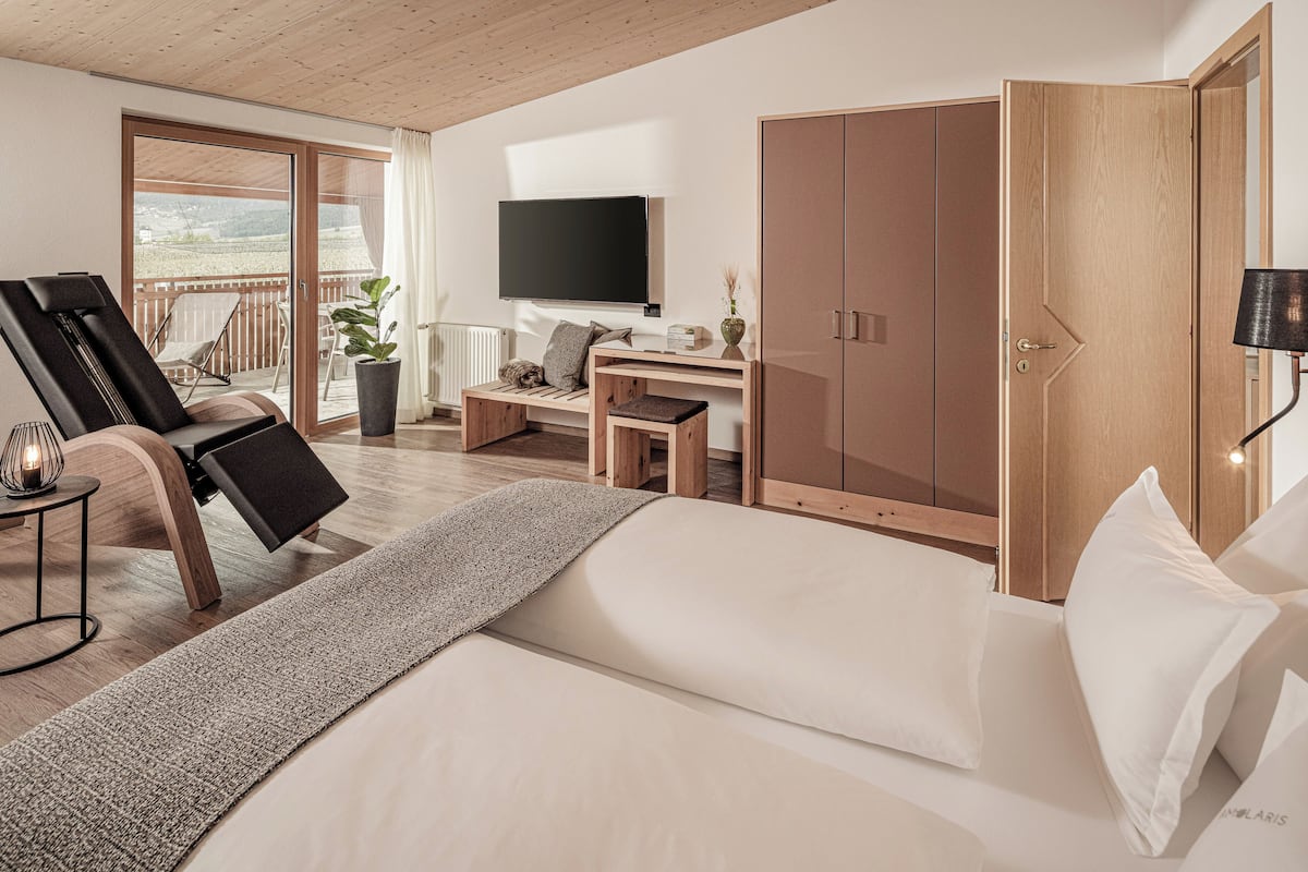 Een moderne hotelkamer met een groot bed, een bureau, een televisie en een balkon met uitzicht.
