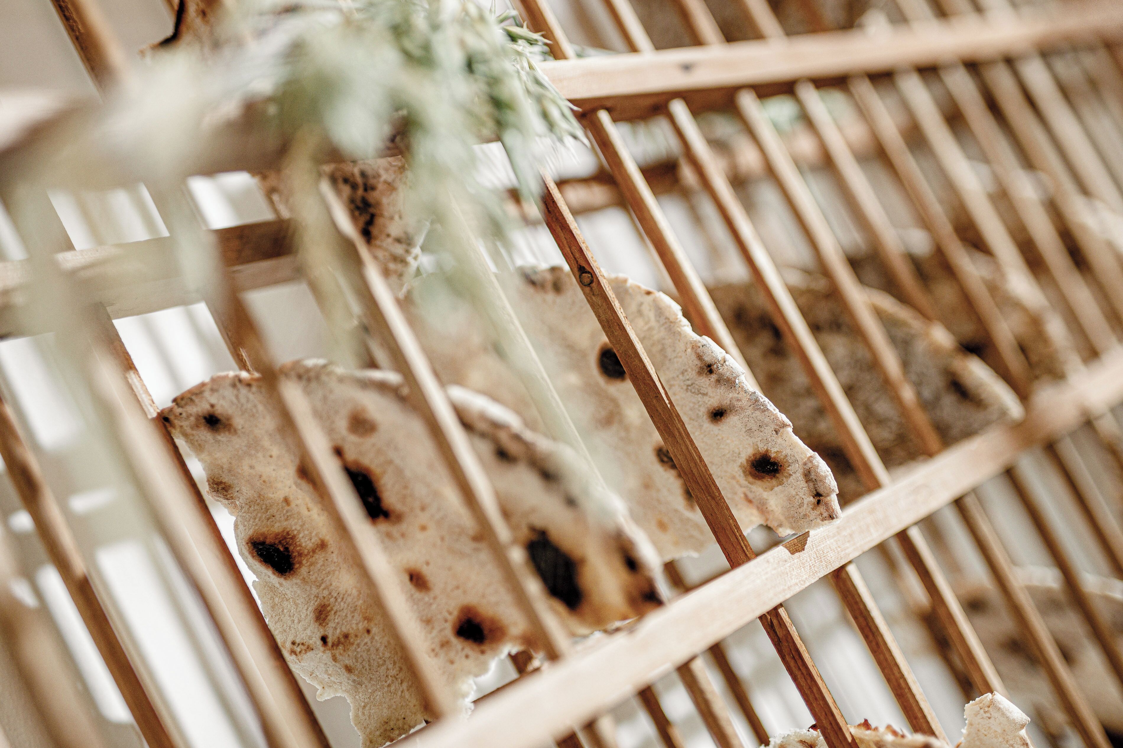 A close-up of a wooden rack with several pieces of flatbread.