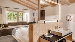 Une salle de bain moderne avec un meuble-lavabo en bois, un grand miroir, une baignoire et une fenêtre avec des rideaux.