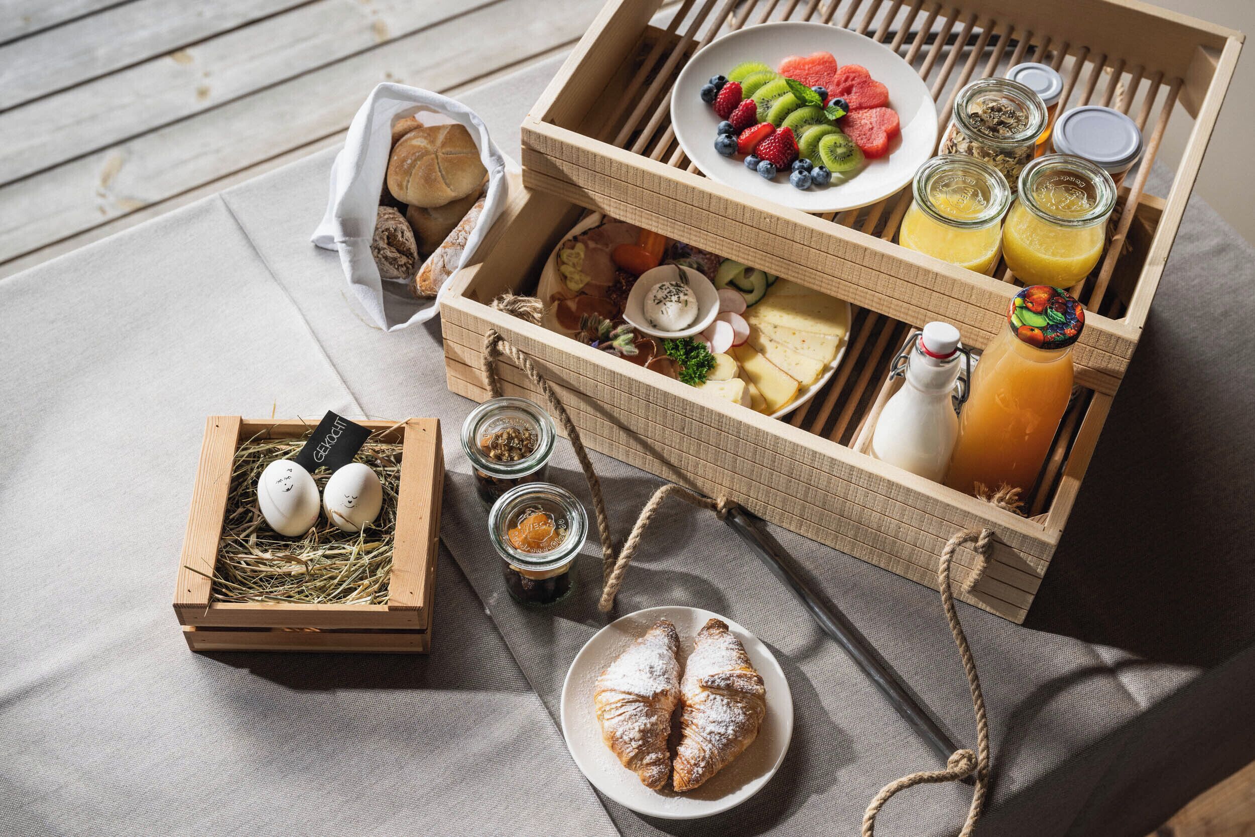 Una mesa de desayuno con pasteles, frutas y bebidas en cajas de madera.