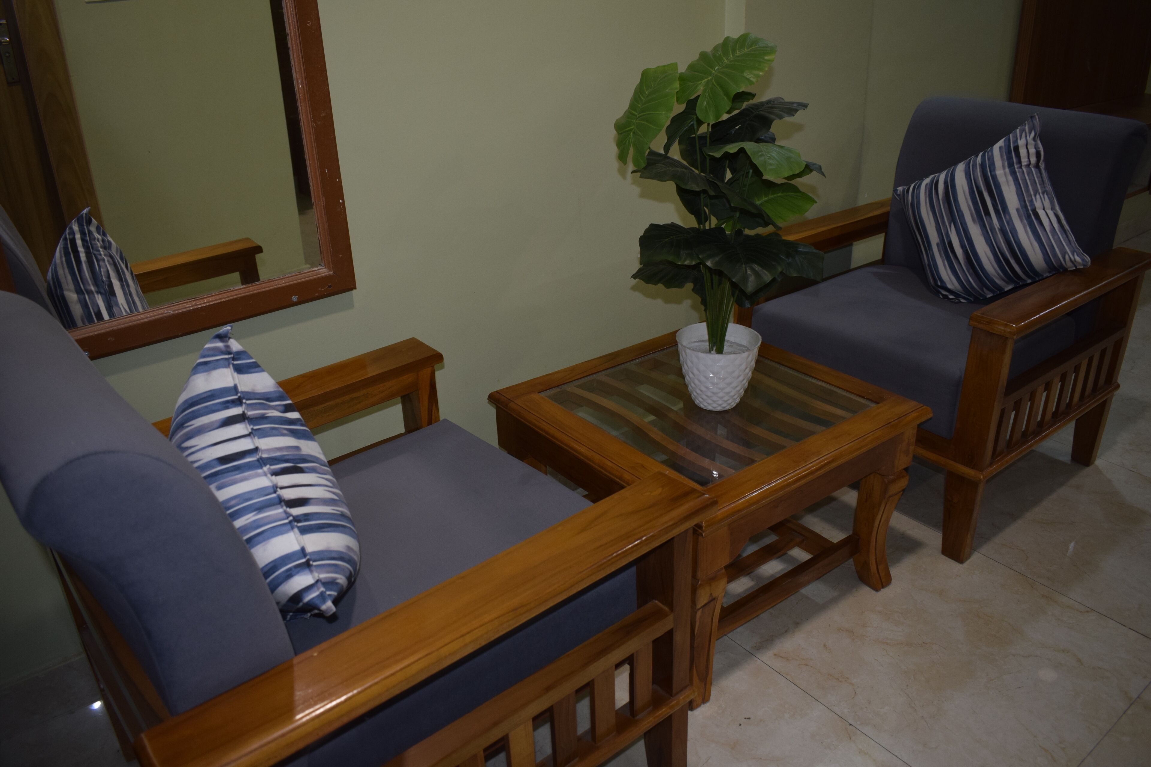 Ein Wohnzimmer mit einer Couch, einem Sessel und einem kleinen Tisch mit einer Pflanze.