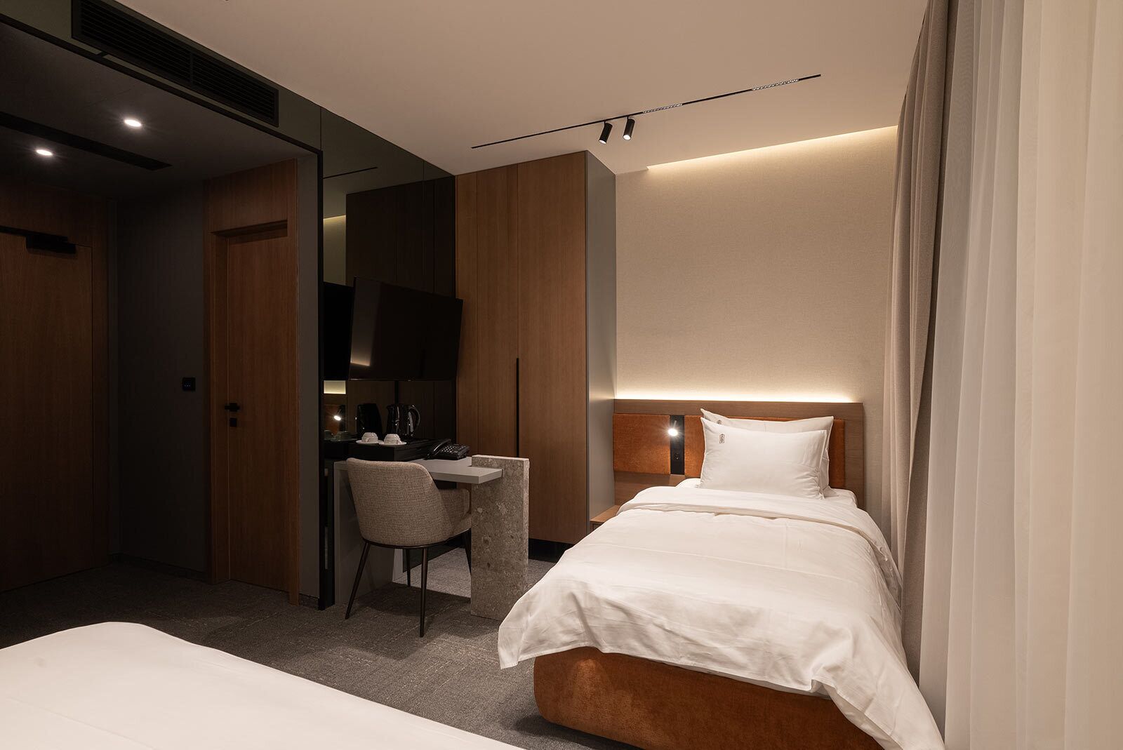 A modern hotel room with a bed, a desk, and a television.