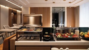 A buffet setup with various food items, a coffee machine, and seating area in a modern hotel room. - Garni Hotel Galeria  (Banja Luka)