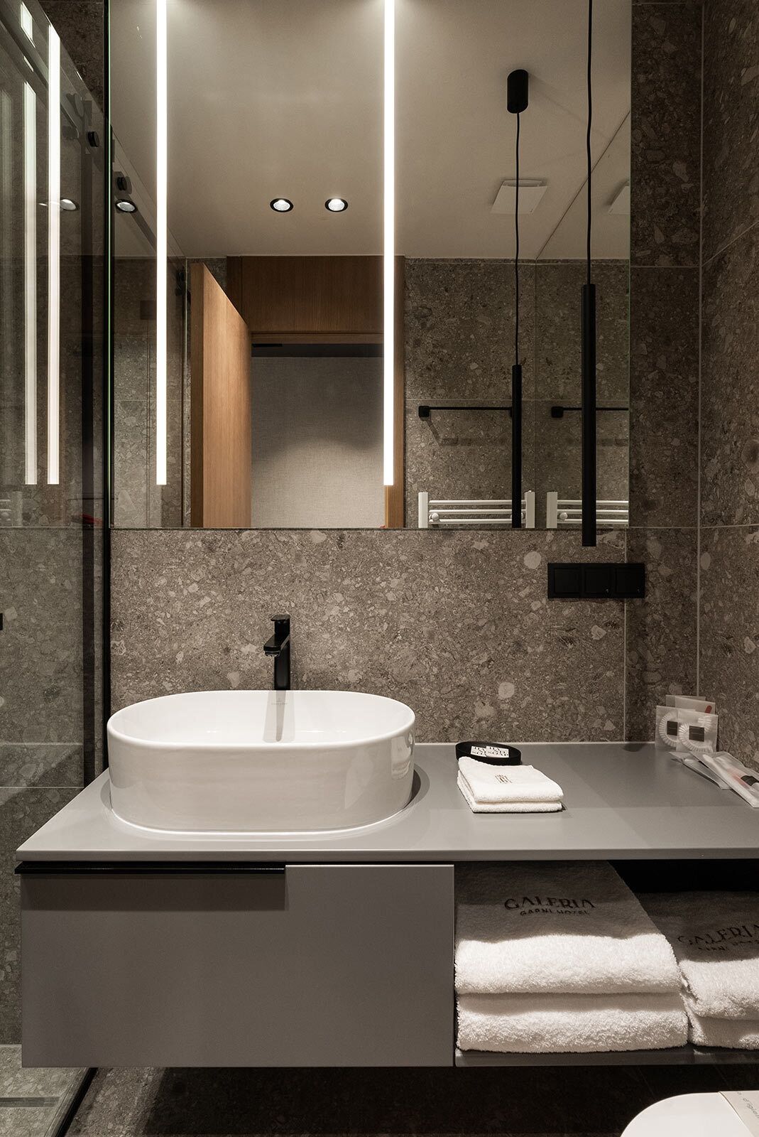 A modern bathroom with a round sink, a mirror, and a towel rack.