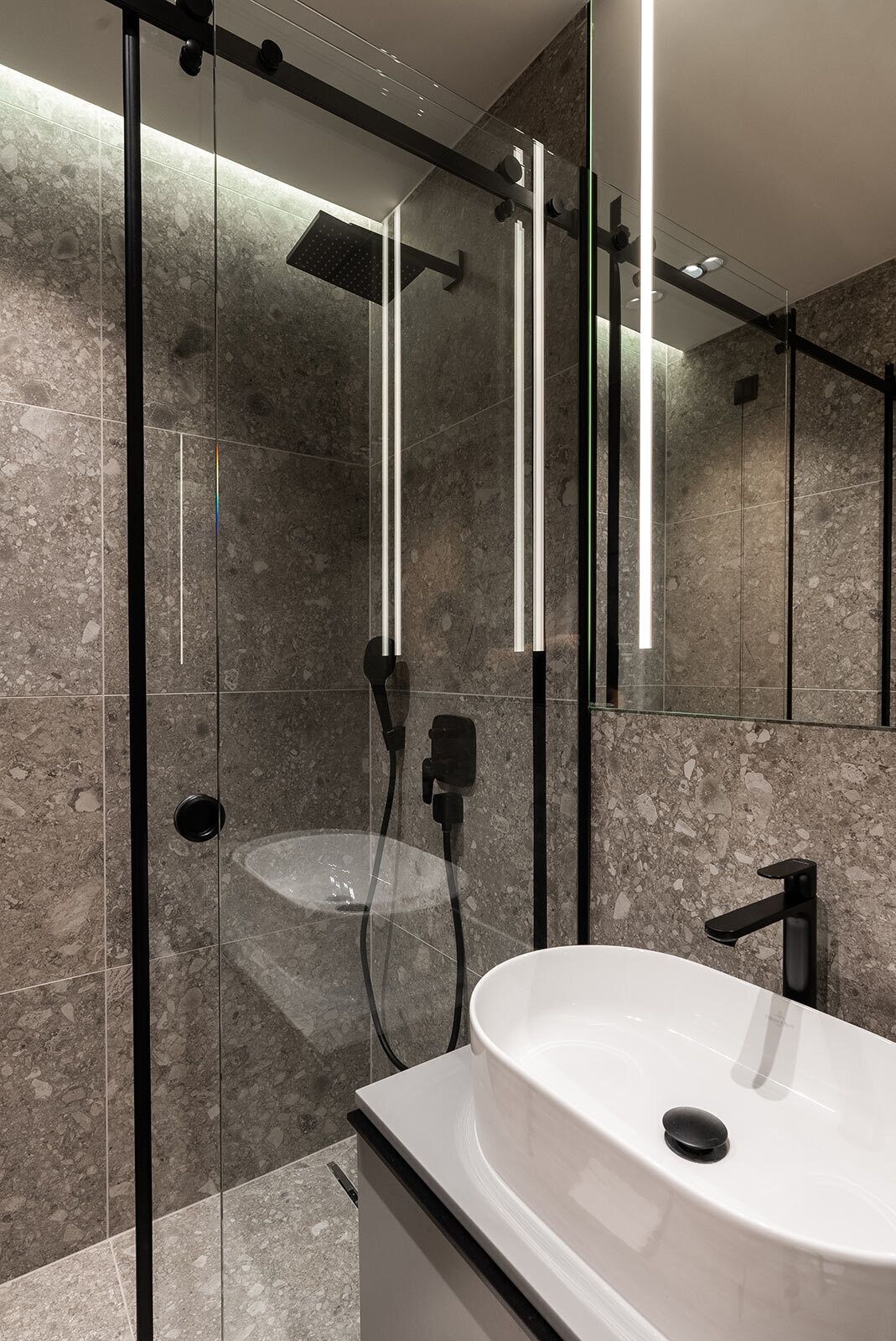 Een moderne badkamer met een douche met glazen wand, een wit wastafelmeubel en een grote spiegel.